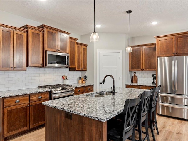 16524 Piper Ln, Brainerd, MN 56401 - kitchen featuring appliances with stainless steel finishes, a sink, light wood-style floors, backsplash, and light stone countertops