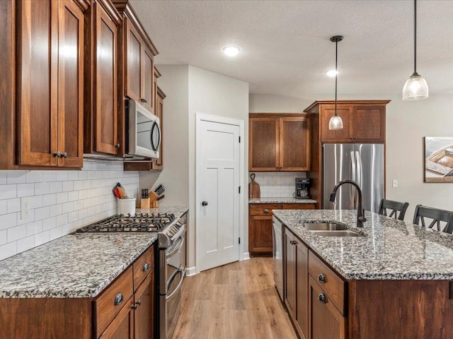 16524 Piper Ln, Brainerd, MN 56401 - kitchen with appliances with stainless steel finishes, a sink, light wood-style flooring, backsplash, and an island with sink