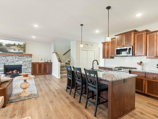 16524 Piper Ln, Brainerd, MN 56401 - kitchen with stainless steel appliances, a sink, open floor plan, brown cabinets, and light stone counters