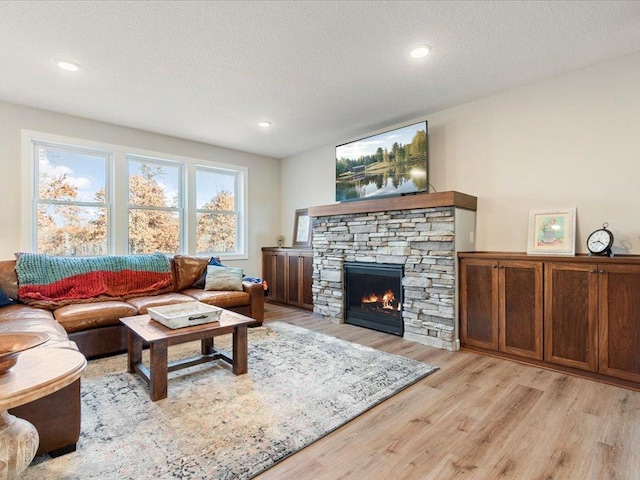 16524 Piper Ln, Brainerd, MN 56401 - living area featuring light wood-style flooring, a stone fireplace, a textured ceiling, and recessed lighting