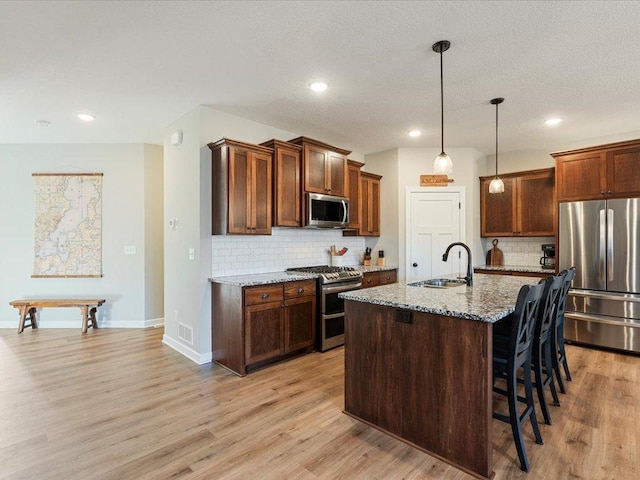 16524 Piper Ln, Brainerd, MN 56401 - kitchen with appliances with stainless steel finishes, a sink, tasteful backsplash, a breakfast bar area, and light stone countertops