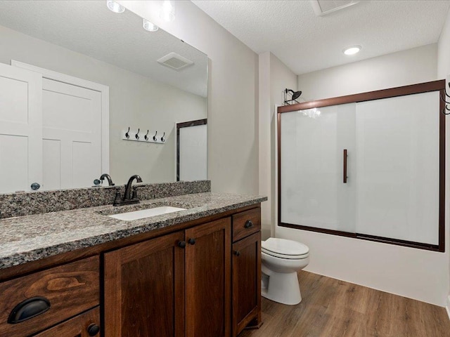16524 Piper Ln, Brainerd, MN 56401 - full bath with wood finished floors, toilet, vanity, combined bath / shower with glass door, and a textured ceiling