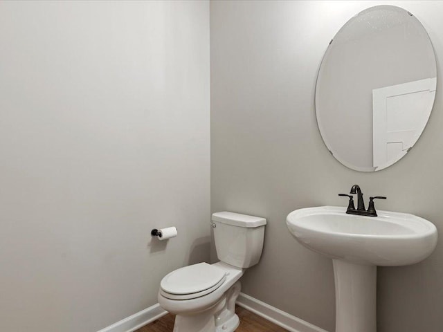 16524 Piper Ln, Brainerd, MN 56401 - bathroom with wood finished floors, toilet, baseboards, and a sink