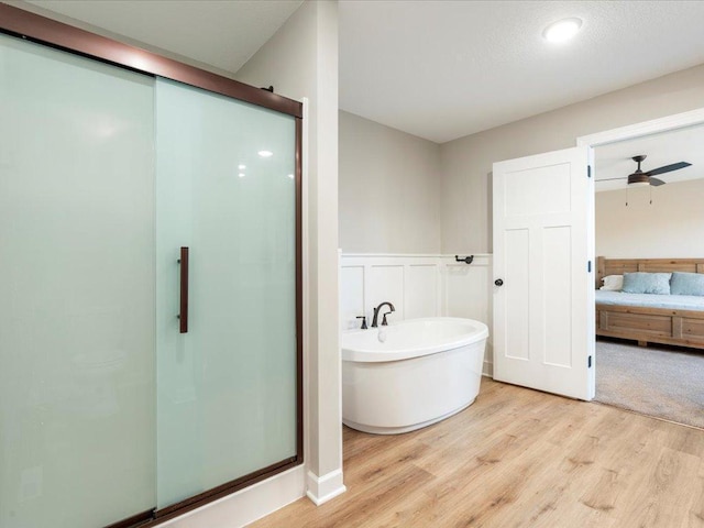 16524 Piper Ln, Brainerd, MN 56401 - full bathroom featuring a shower stall, wood finished floors, a freestanding bath, a wainscoted wall, and a decorative wall