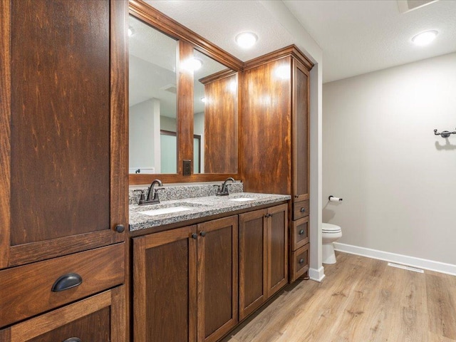 16524 Piper Ln, Brainerd, MN 56401 - bathroom featuring wood finished floors, toilet, baseboards, and double vanity