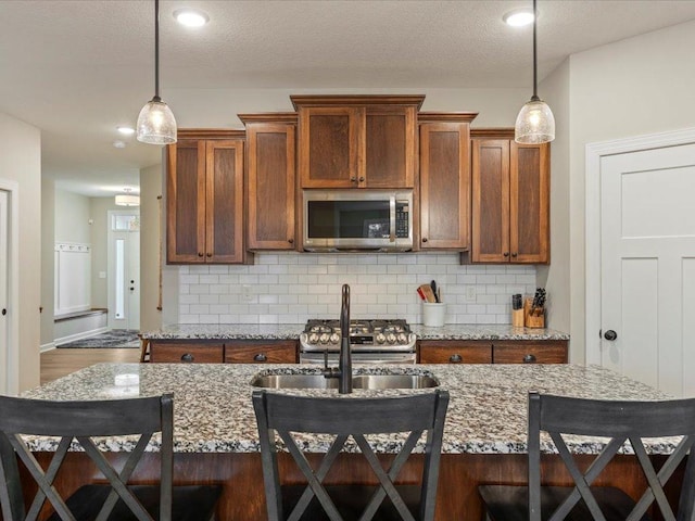 16524 Piper Ln, Brainerd, MN 56401 - kitchen with stainless steel microwave, a kitchen breakfast bar, a sink, brown cabinets, and recessed lighting