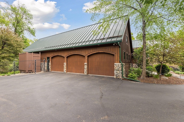 2442 Meeting St, Minnetonka, MN 55391 - view of side of property with a standing seam roof, a garage, stone siding, and metal roof