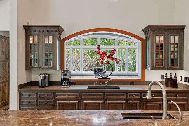 2442 Meeting St, Minnetonka, MN 55391 - kitchen with dark brown cabinets, glass insert cabinets, a sink, and dark countertops