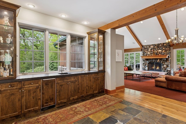 2442 Meeting St, Minnetonka, MN 55391 - bar featuring a sink, dark wood-style floors, a chandelier, baseboards, and a stone fireplace