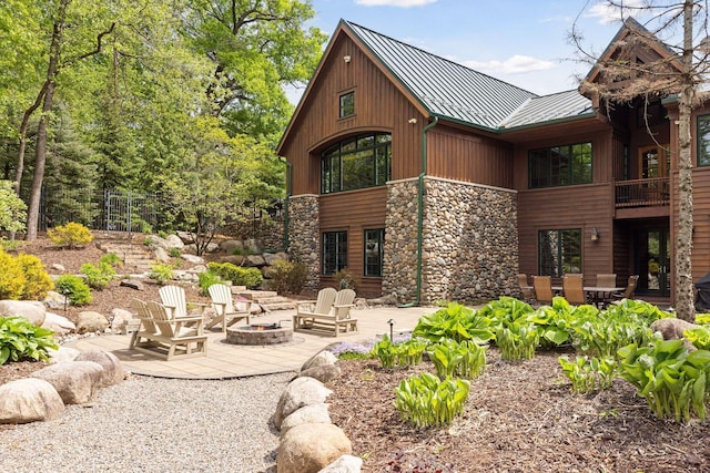 2442 Meeting St, Minnetonka, MN 55391 - back of house with a standing seam roof, stone siding, a fire pit, a patio, and metal roof