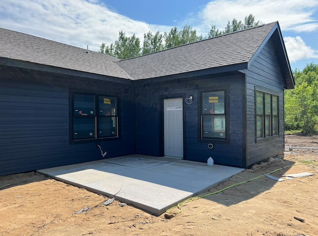 rear view of property featuring roof with shingles and a patio