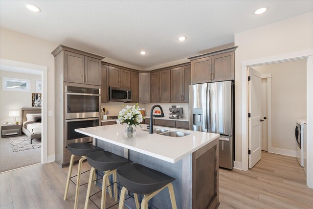 2300 Old Bridge Ln, Hastings, MN 55033 - kitchen featuring appliances with stainless steel finishes, separate washer and dryer, a sink, light wood-type flooring, and recessed lighting