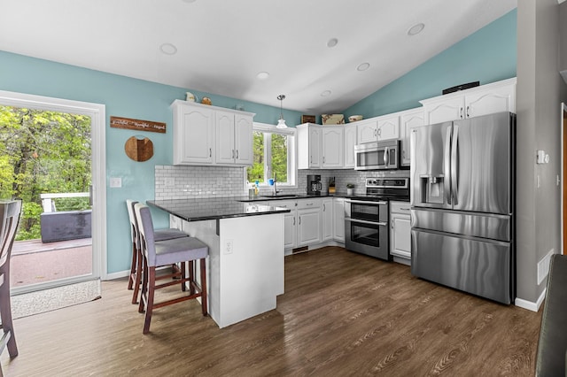 14465 Blackberry Ct, Baxter, MN 56425 - kitchen featuring appliances with stainless steel finishes, a peninsula, decorative backsplash, dark countertops, and white cabinetry