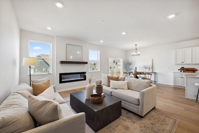 6570 Jody Ave S, Cottage Grove, MN 55016 - living room with a chandelier, a glass covered fireplace, light wood finished floors, and recessed lighting