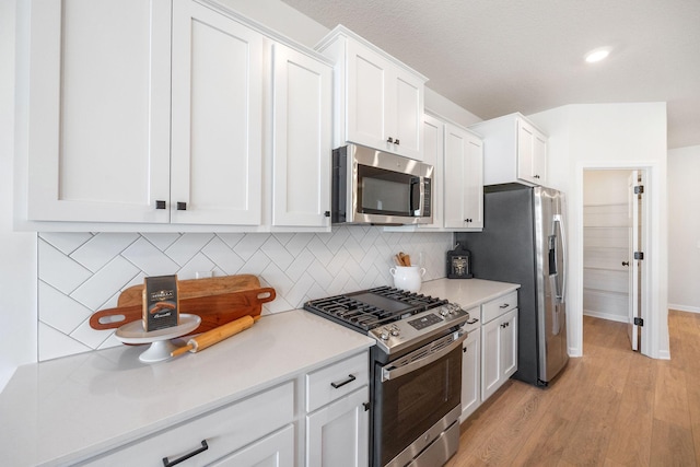 6570 Jody Ave S, Cottage Grove, MN 55016 - kitchen featuring appliances with stainless steel finishes, light wood-type flooring, white cabinetry, tasteful backsplash, and light countertops