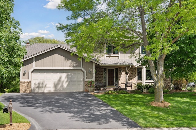 4650 Cottonwood Ln N, Plymouth, MN 55442 - view of front facade featuring brick siding, an attached garage, asphalt driveway, and a front lawn