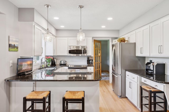 4650 Cottonwood Ln N, Plymouth, MN 55442 - kitchen featuring appliances with stainless steel finishes, light wood-style floors, white cabinetry, a peninsula, and decorative backsplash