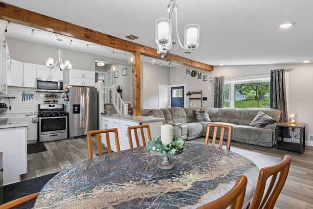 dining space featuring a chandelier, beamed ceiling, wood finished floors, and recessed lighting