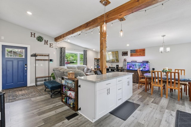kitchen featuring open floor plan, light wood-style flooring, white cabinets, decorative light fixtures, and light stone countertops