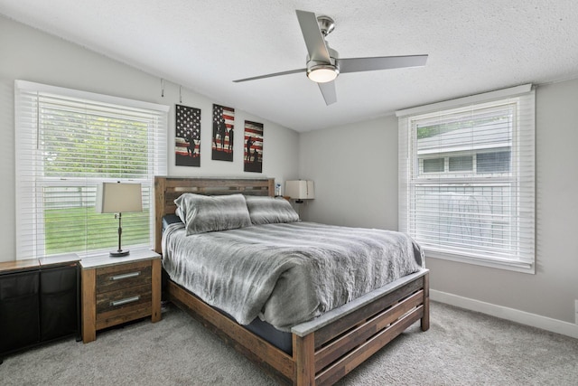 bedroom featuring multiple windows, light carpet, baseboards, a textured ceiling, and a ceiling fan
