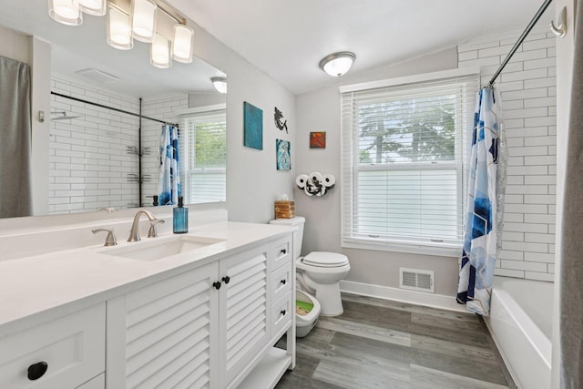 full bath with toilet, plenty of natural light, lofted ceiling, wood finished floors, and vanity