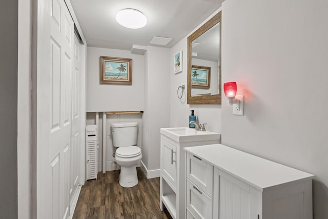 bathroom with toilet, wood finished floors, vanity, and baseboards
