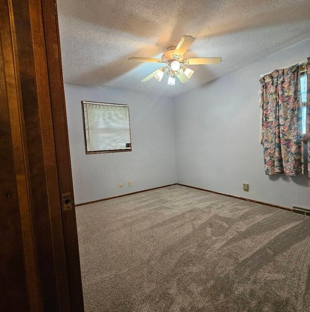 701 10th St NE, Austin, MN 55912 - empty room featuring carpet, a textured ceiling, a ceiling fan, and baseboards