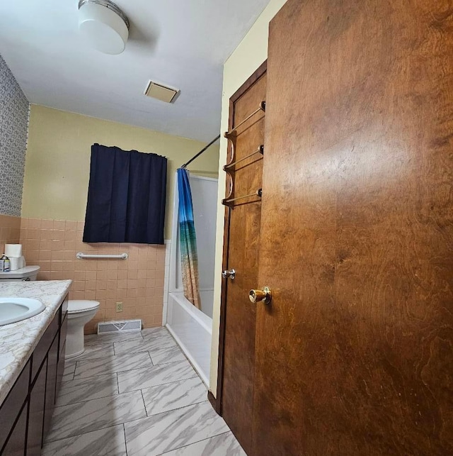 701 10th St NE, Austin, MN 55912 - full bathroom with toilet, tile walls, vanity, shower / tub combo with curtain, and marble finish floors