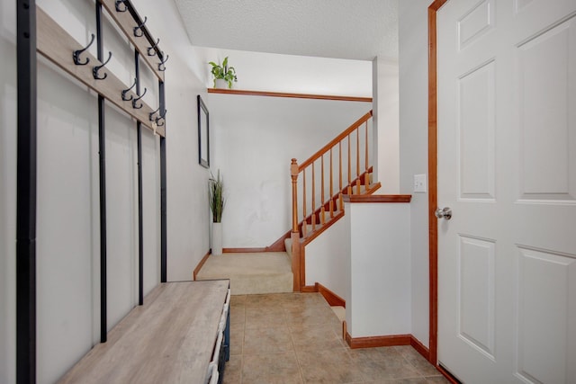 5133 Farnham Dr N, Hugo, MN 55038 - mudroom featuring light tile patterned flooring, a textured ceiling, light colored carpet, and baseboards
