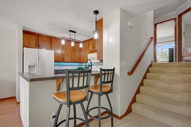 5133 Farnham Dr N, Hugo, MN 55038 - kitchen with white appliances, dark countertops, a peninsula, a textured ceiling, and a kitchen breakfast bar