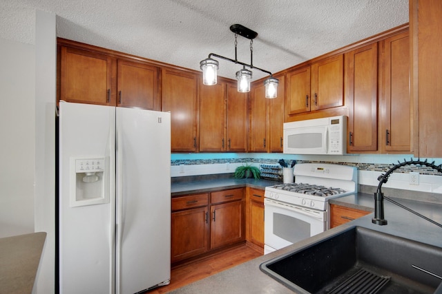 5133 Farnham Dr N, Hugo, MN 55038 - kitchen with white appliances, a sink, a textured ceiling, brown cabinetry, and dark countertops