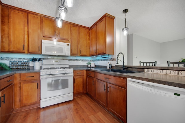 5133 Farnham Dr N, Hugo, MN 55038 - kitchen featuring white appliances, a sink, dark countertops, brown cabinets, and a textured ceiling