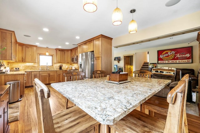 2511 Carver Ave E, Maplewood, MN 55119 - kitchen with appliances with stainless steel finishes, a kitchen bar, light wood-style flooring, and recessed lighting