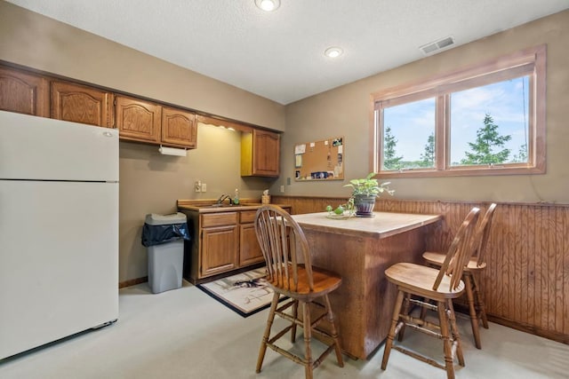 2511 Carver Ave E, Maplewood, MN 55119 - kitchen with freestanding refrigerator, brown cabinetry, light colored carpet, a textured ceiling, and recessed lighting