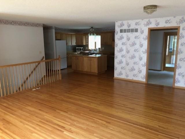 2023 Woodcrest Ln SW, Rochester, MN 55902 - kitchen featuring freestanding refrigerator, wallpapered walls, light wood-type flooring, stainless steel microwave, and baseboards