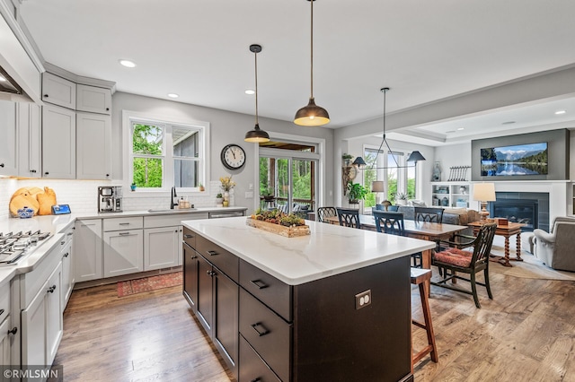 7023 61st St S, Cottage Grove, MN 55016 - kitchen featuring a sink, light wood-type flooring, a breakfast bar area, tasteful backsplash, and plenty of natural light