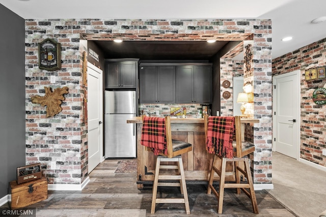 7023 61st St S, Cottage Grove, MN 55016 - kitchen featuring freestanding refrigerator, brick wall, baseboards, a kitchen bar, and recessed lighting