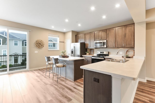 2189 Gateway Hill Rd N, Saint Paul, MN 55109 - kitchen with stainless steel appliances, a sink, a breakfast bar area, light countertops, and light wood finished floors
