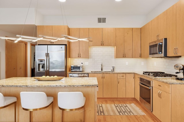 1240 2nd St Unit 822, Minneapolis, MN 55415 - kitchen featuring stainless steel appliances, a sink, light wood finished floors, a breakfast bar area, and tasteful backsplash