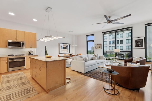 1240 2nd St Unit 822, Minneapolis, MN 55415 - kitchen with stainless steel appliances, light brown cabinetry, open floor plan, light wood finished floors, and a kitchen island