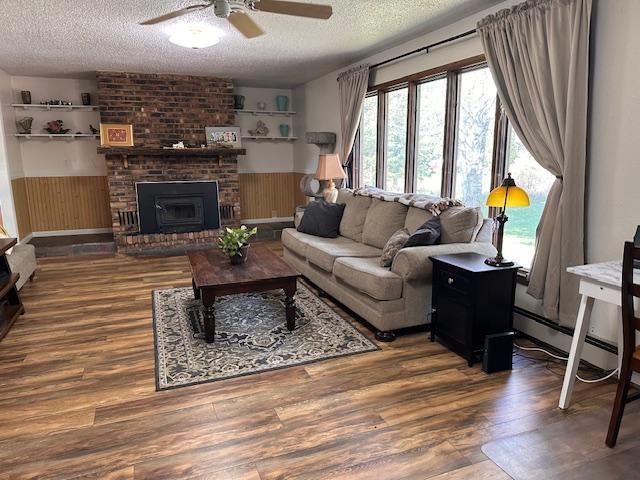 22 Cottonwood Ct, Babbitt, MN 55706 - living area with a textured ceiling, a ceiling fan, wainscoting, wood finished floors, and wooden walls
