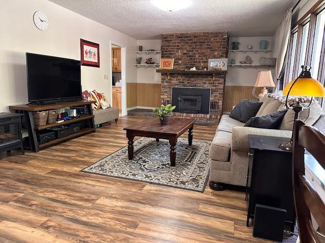 22 Cottonwood Ct, Babbitt, MN 55706 - living room featuring a textured ceiling, wainscoting, wood finished floors, and a fireplace