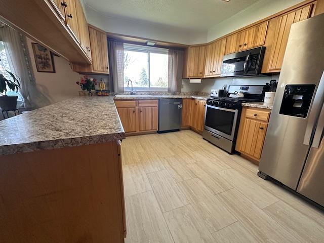 22 Cottonwood Ct, Babbitt, MN 55706 - kitchen featuring stainless steel appliances, a sink, brown cabinetry, and light flooring