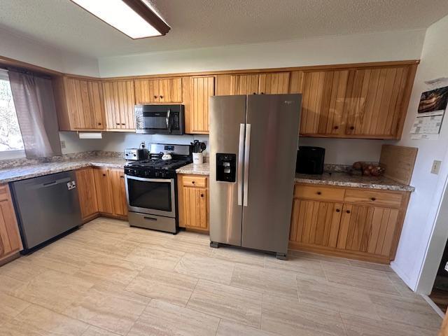 22 Cottonwood Ct, Babbitt, MN 55706 - kitchen featuring appliances with stainless steel finishes, brown cabinets, and light stone countertops