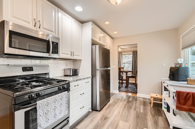 4989 Turtle Ln W, Shoreview, MN 55126 - kitchen featuring stainless steel appliances, light wood finished floors, white cabinetry, tasteful backsplash, and light stone counters