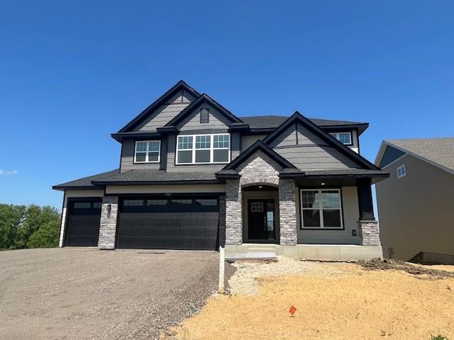 6743 Tamarack Ln, Corcoran, MN 55340 - craftsman-style home with stone siding, an attached garage, a porch, and driveway