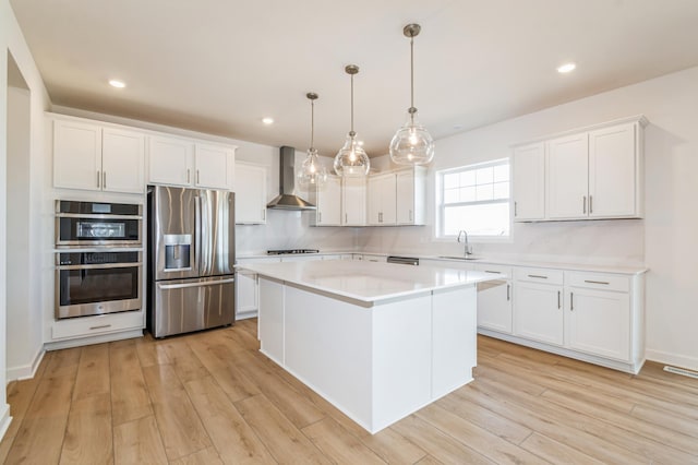 6743 Tamarack Ln, Corcoran, MN 55340 - kitchen with appliances with stainless steel finishes, wall chimney exhaust hood, light wood-style flooring, a center island, and recessed lighting