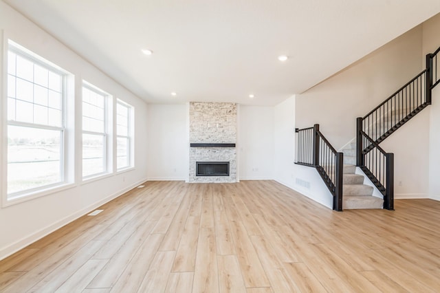 6743 Tamarack Ln, Corcoran, MN 55340 - unfurnished living room with light wood-style flooring, stairway, baseboards, recessed lighting, and a stone fireplace