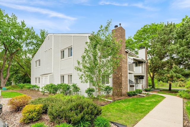 2310 Benson Ave Unit H, Saint Paul, MN 55116 - view of side of home with a lawn, a balcony, and a chimney