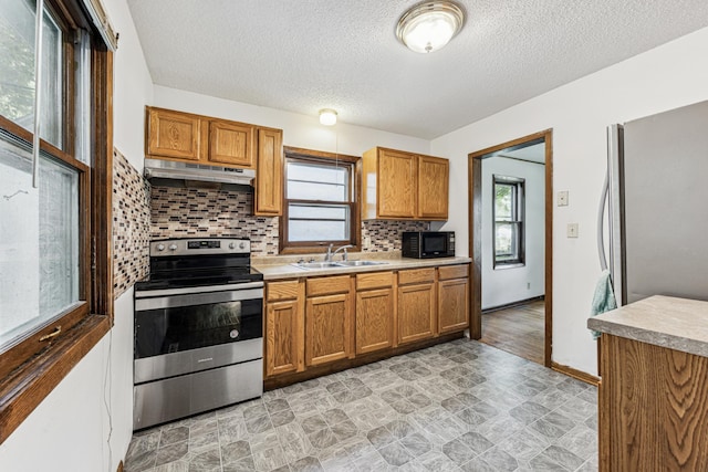 917 Jessie St, Saint Paul, MN 55130 - kitchen with appliances with stainless steel finishes, under cabinet range hood, brown cabinets, healthy amount of natural light, and a textured ceiling